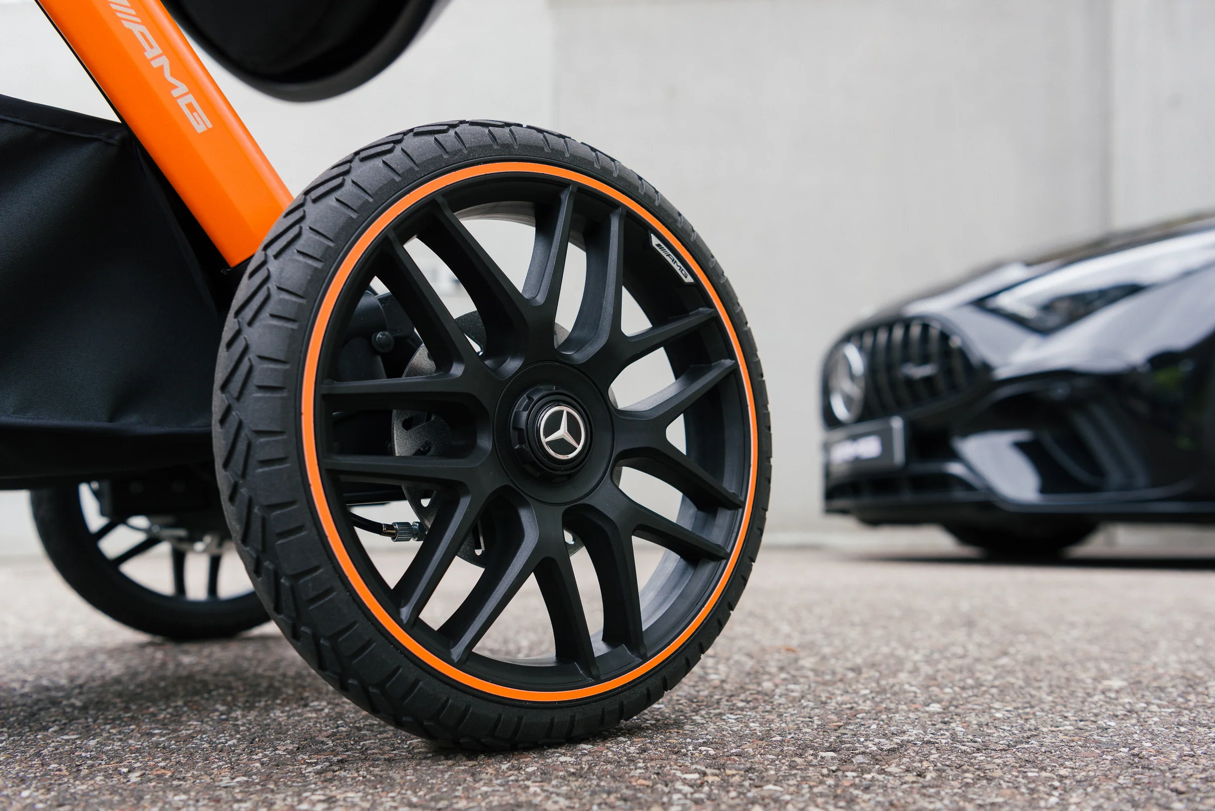 Mercedes yıldızlı jant kapağı ve turuncu şeritli arazi tekerleği — arkada Mercedes-AMG